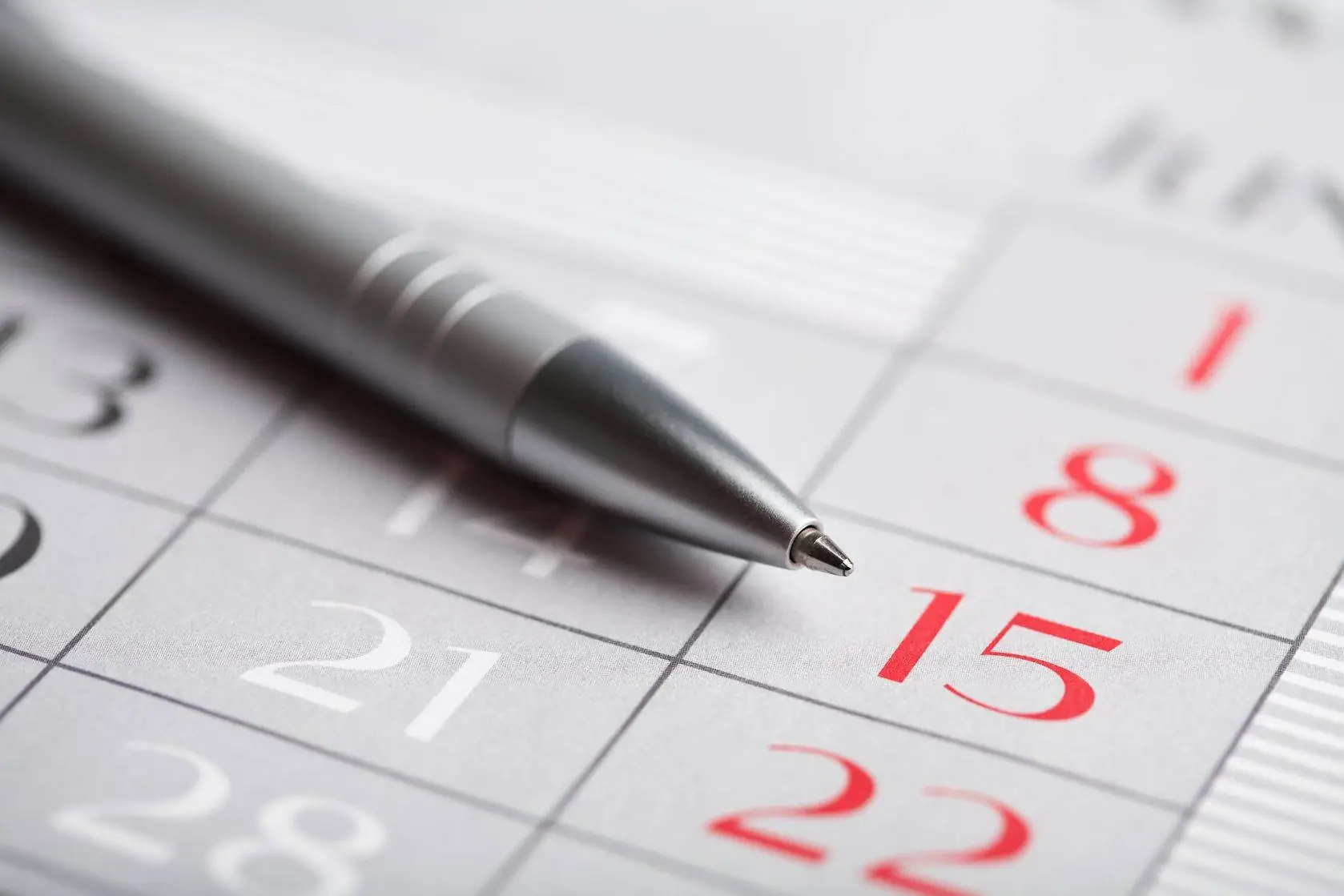 Close up of a pen on a calendar with focus on the 15th.