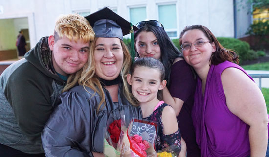20180524_Commencement-332 Female graduate with children and flowers