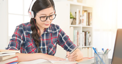 female student studying at home with headphones on