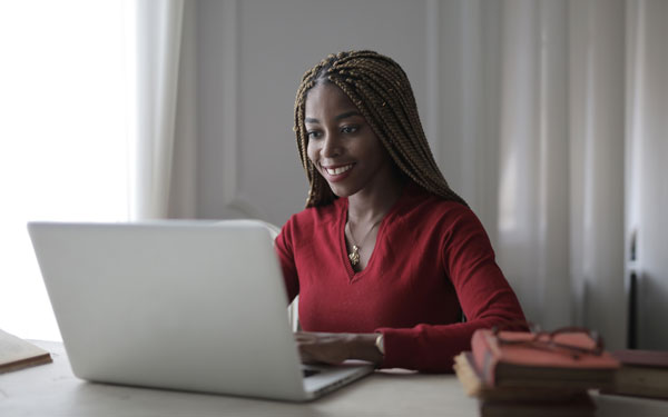 woman using laptop in home office with books on desk
