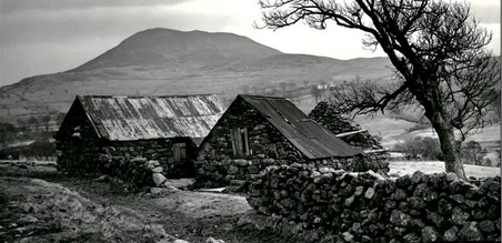 a black and white photo of a stone house in the country