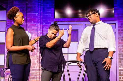three individuals from The Second City performing on stage