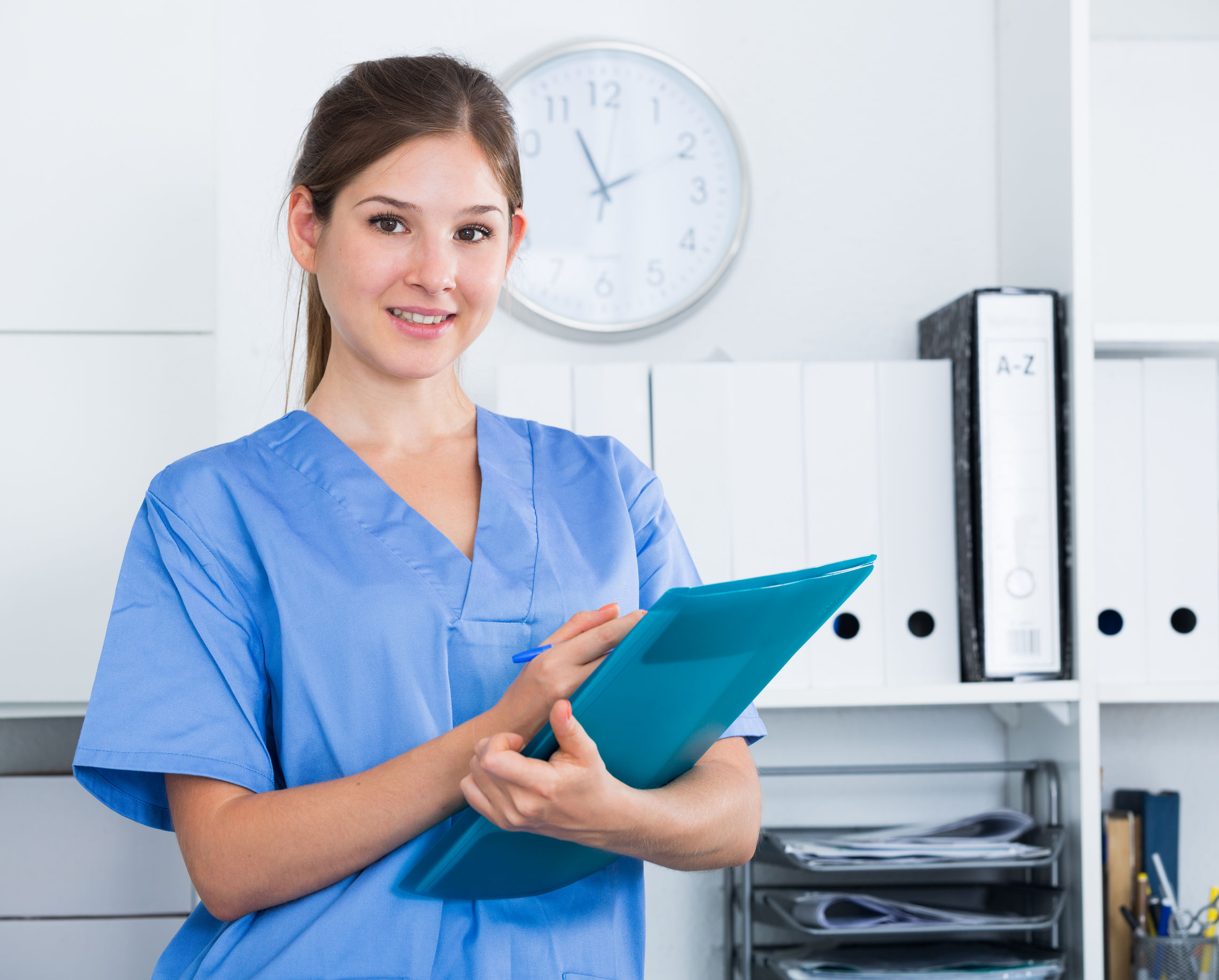 Smiling young female doctor writing notes on clipboard in clinic