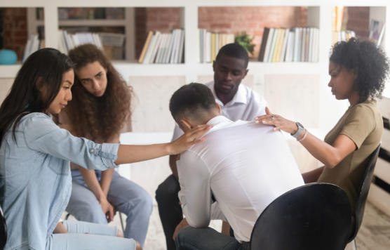 Diverse people support depressed man at group therapy