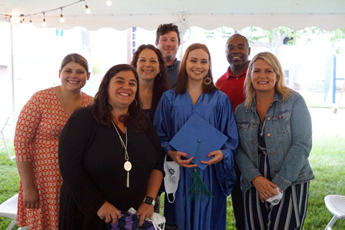 student posing with her family and instructors at the Ocean Achievement center graduation