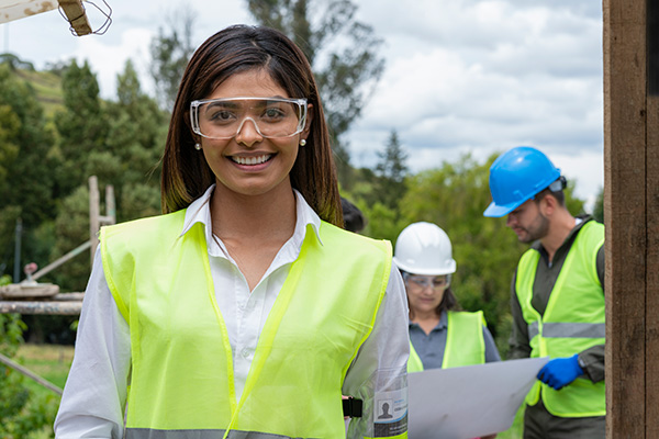 Three people in yellow safety vests on an outdoor work site.