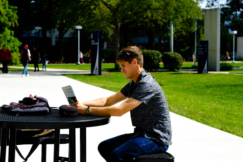 student reading at a picnic table on OCC's campus