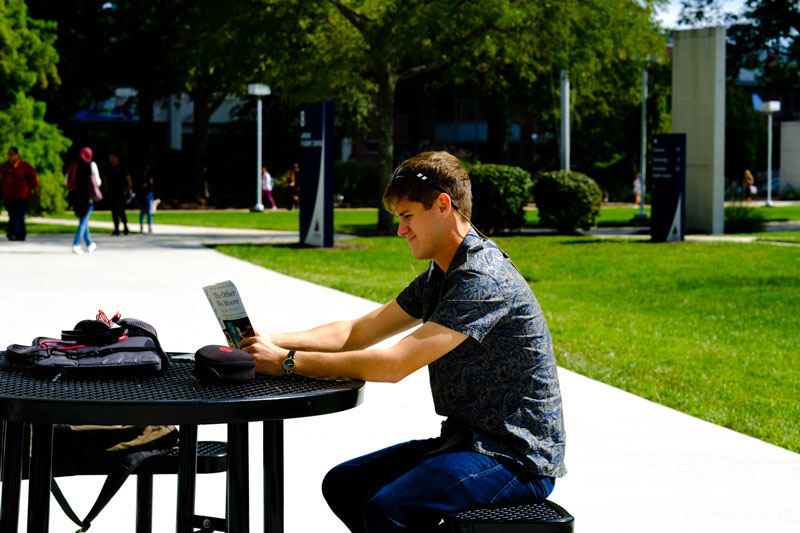 Student-Reading,-Landscape-1 student reading at a picnic table on OCC's campus