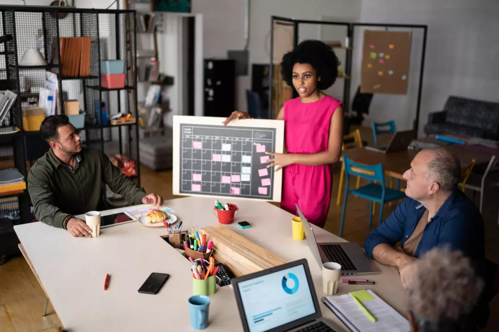 Advanced Project Management Young woman talking in a meeting at work