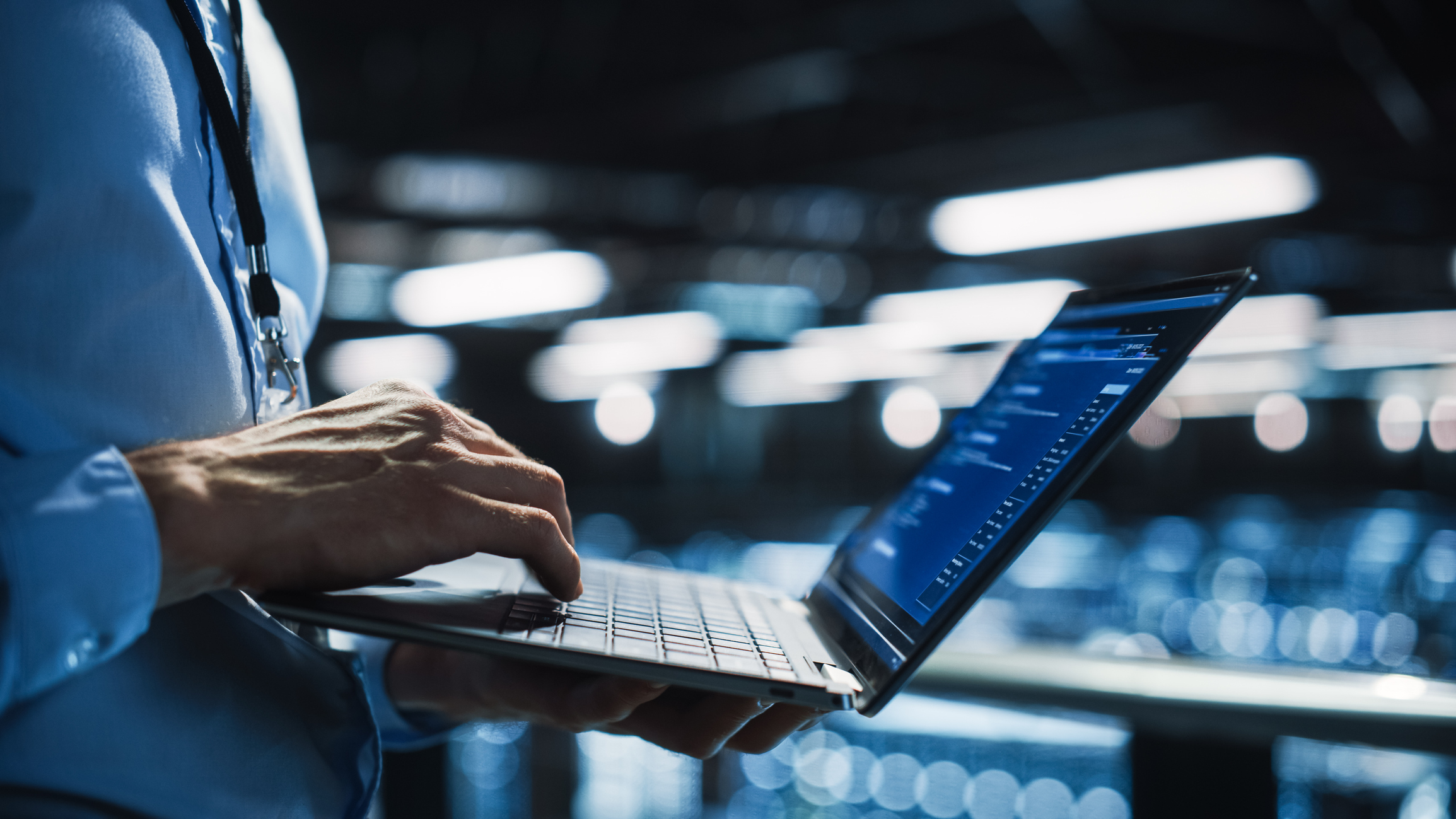 Individual typing on their laptop while standing