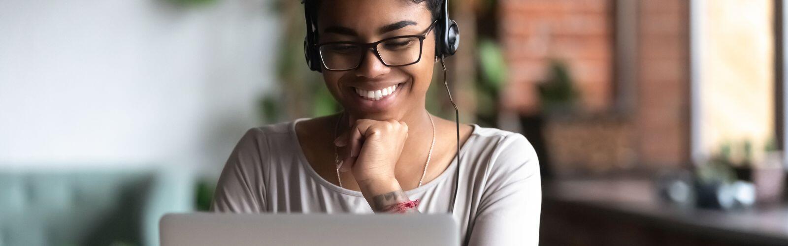 female student sitting at laptop wearing headphones