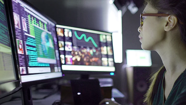 Women working with data on two computer monitors