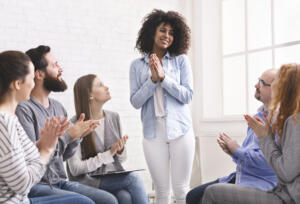 Grateful woman sharing her progress with rehab group at therapy session.