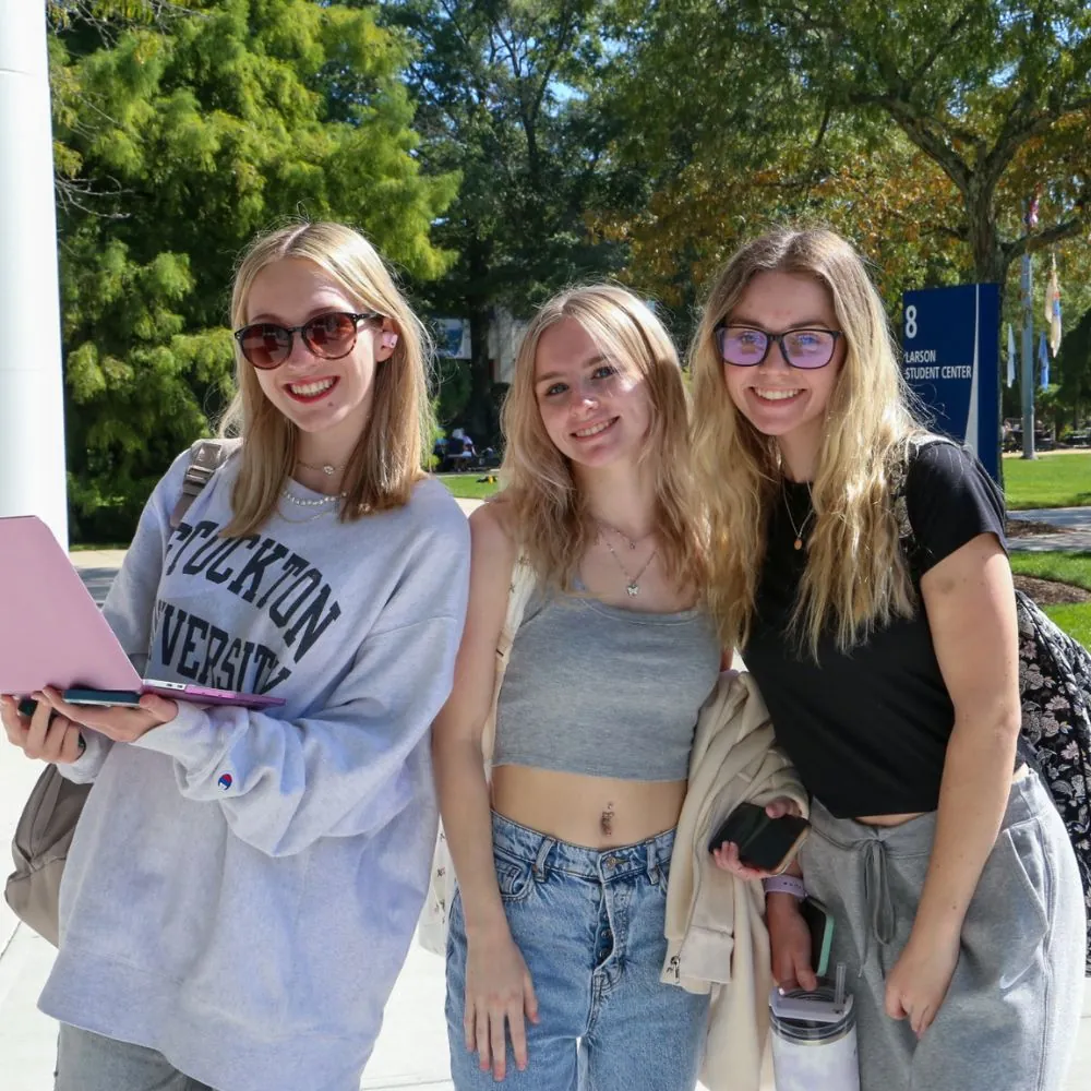 Three students on campus posing for an image