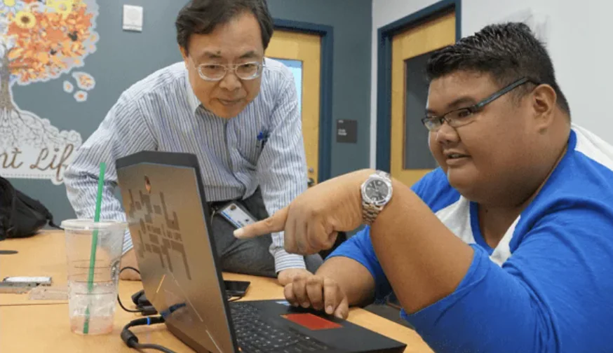 Professor looking at a student's laptop screen as the student points.