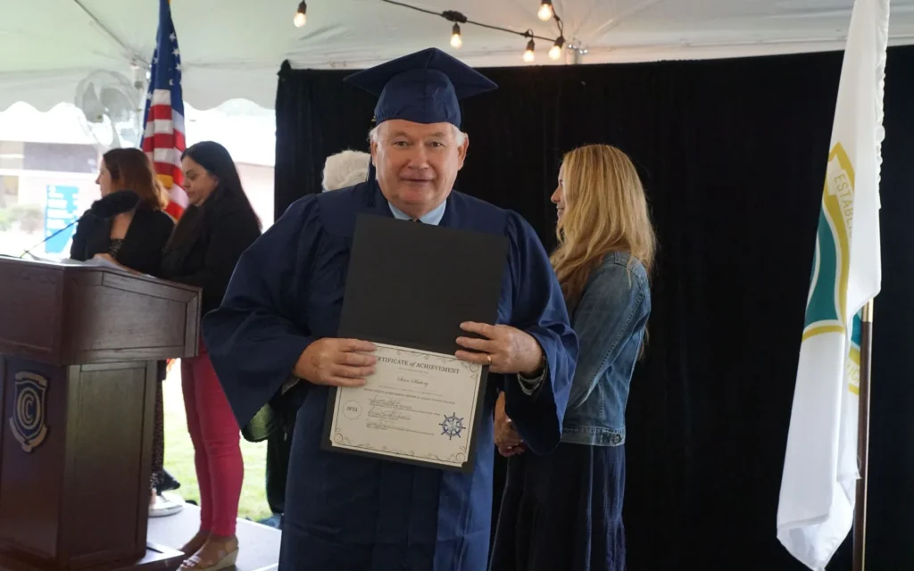Male graduate posing with is diploma at graduation