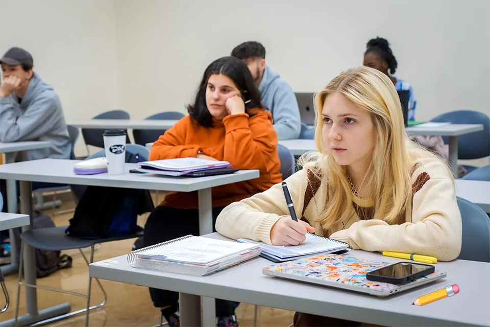Student sitting at table taking notes while paying attention to the lecture