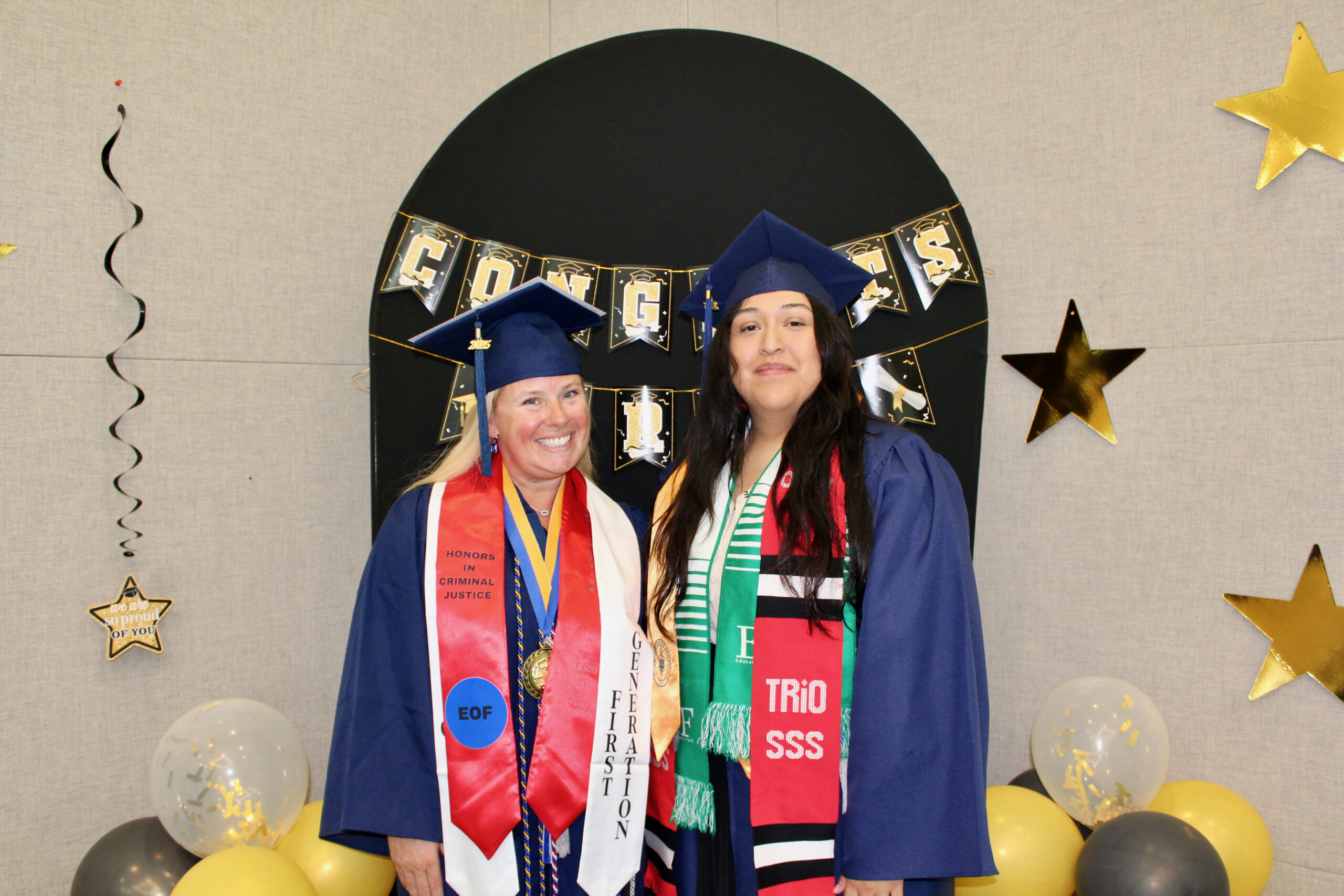 Two students posing together in graduation regalia
