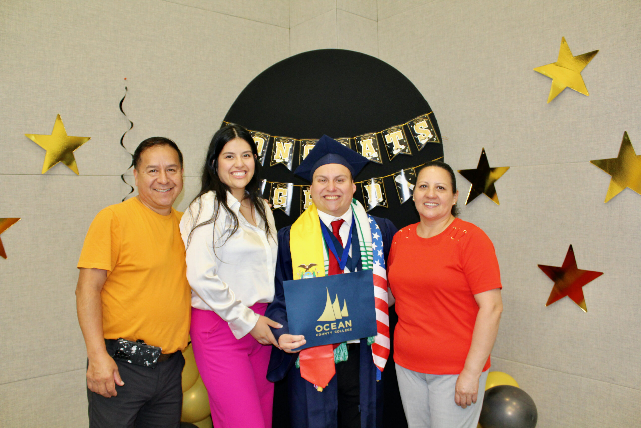 A student posing with his family in graduation regalia