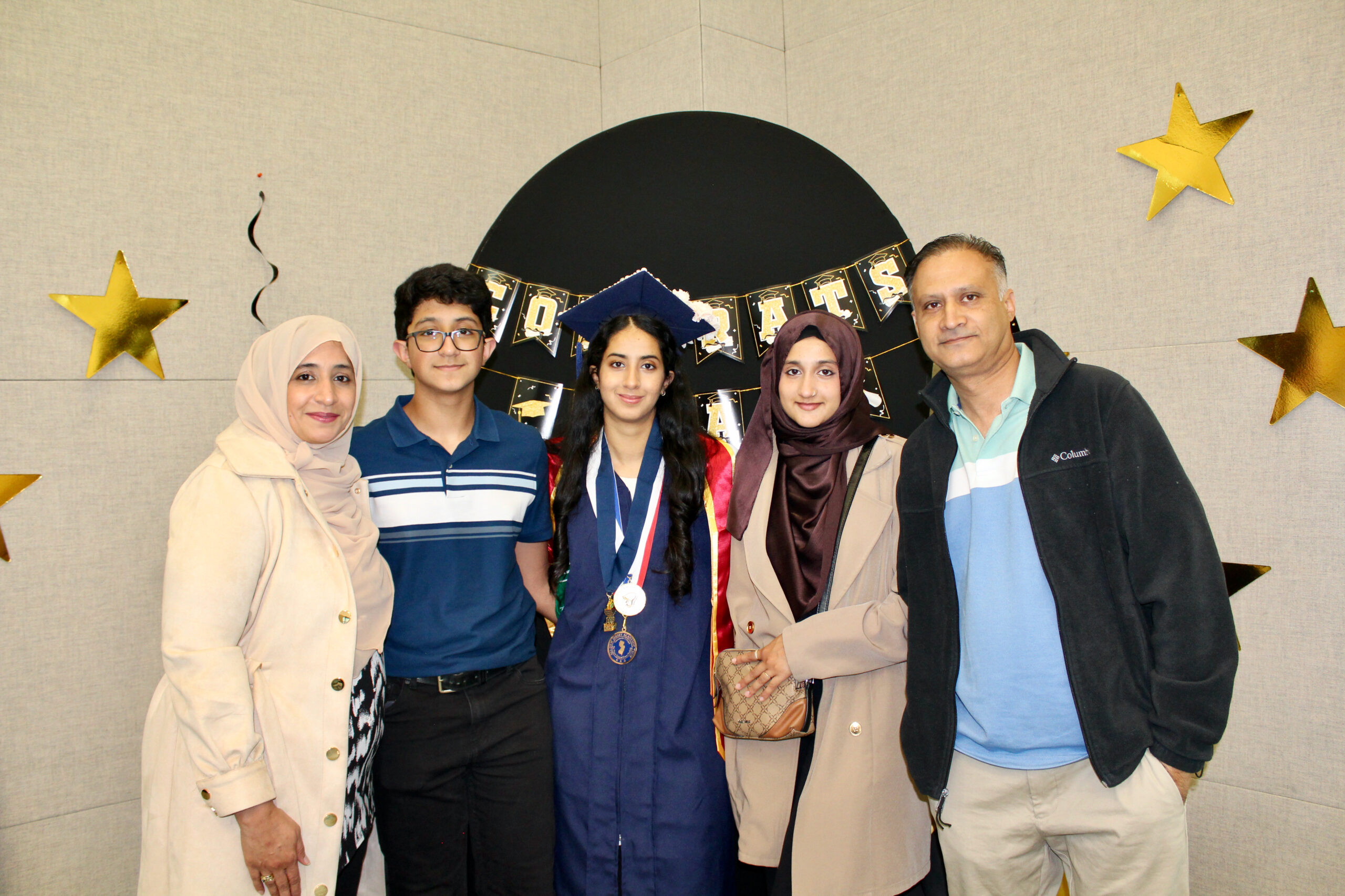 A student posing with her family in graduation regalia