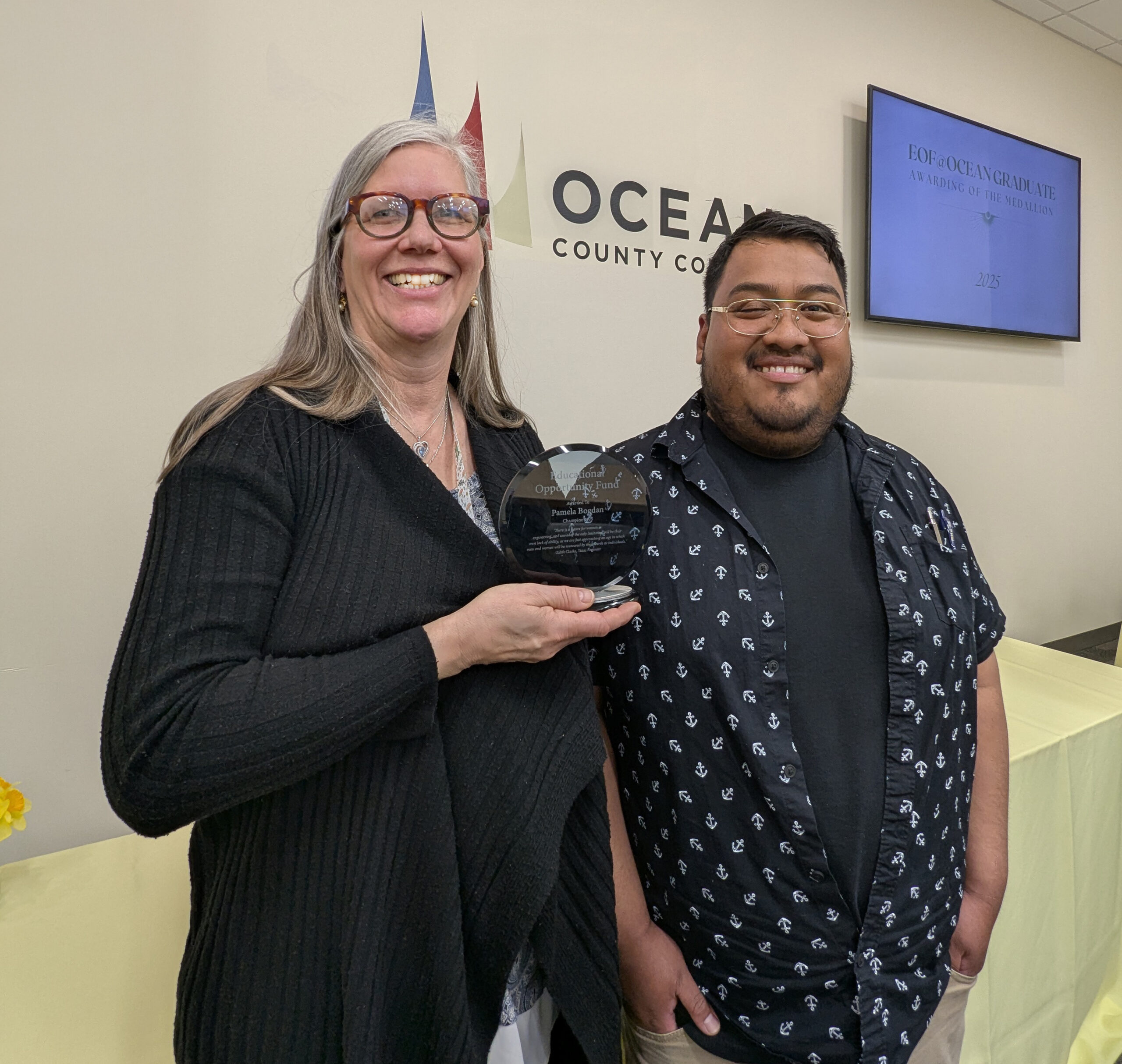 Professor and Student posing with the EOF champion award