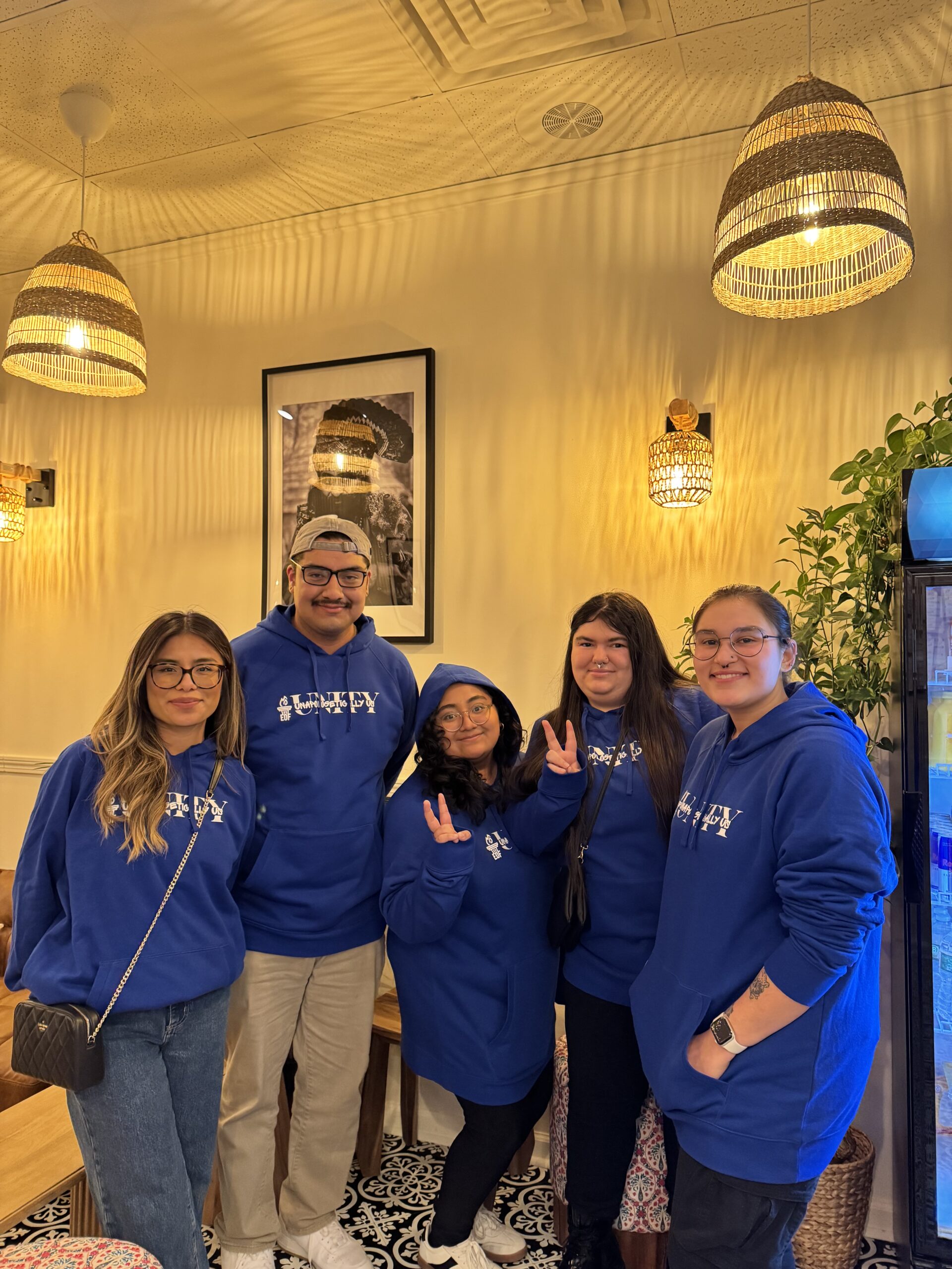 A group of students posing together in matching sweatshirts at a conference.