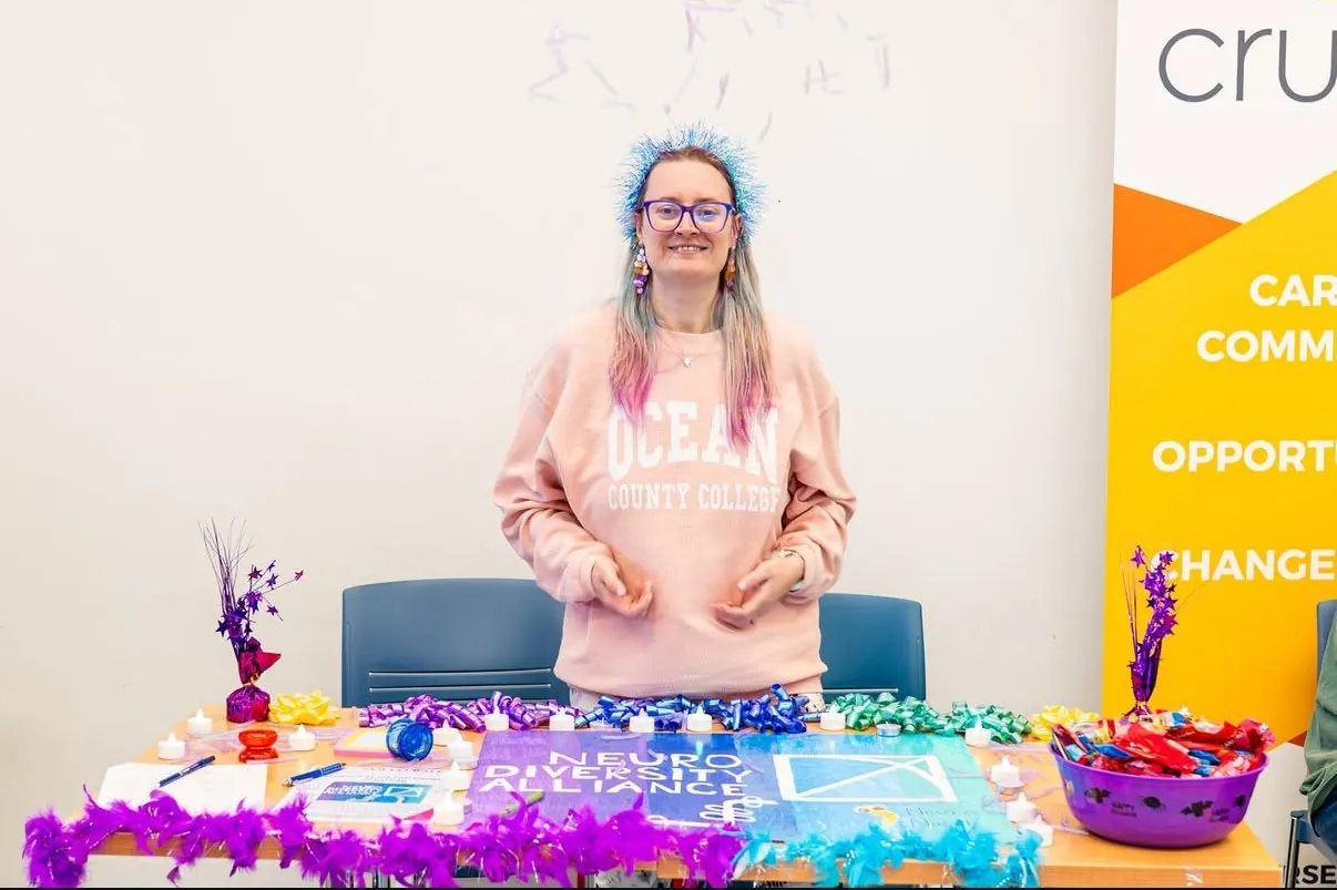 Student wearing an OCC Sweatshirt in front of a table at the club fair. 