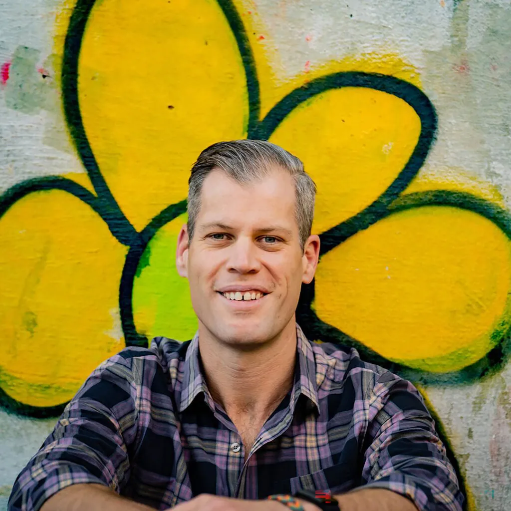 Person in front of a graffiti mural with a large yellow flower.
