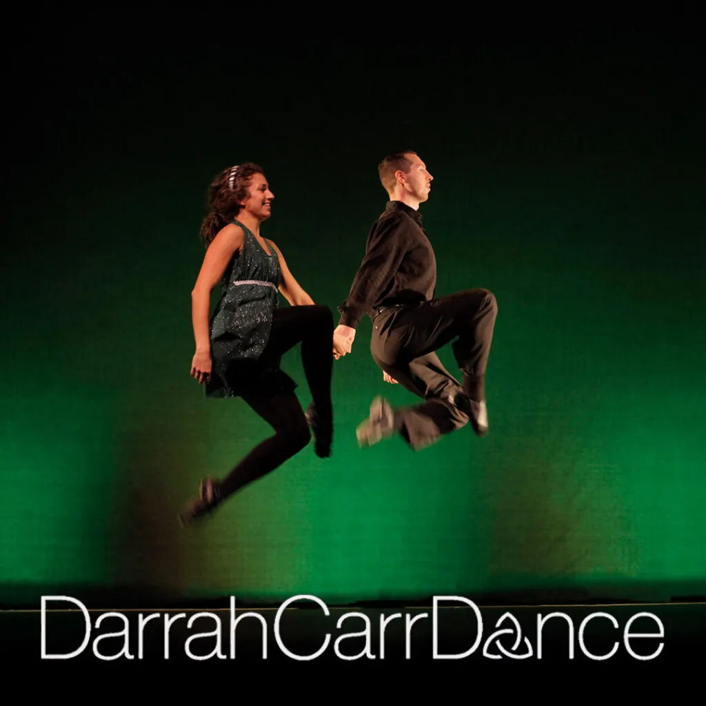 Two dancers leaping in front of a green background. Transcribed Text: DarrahCarrDance