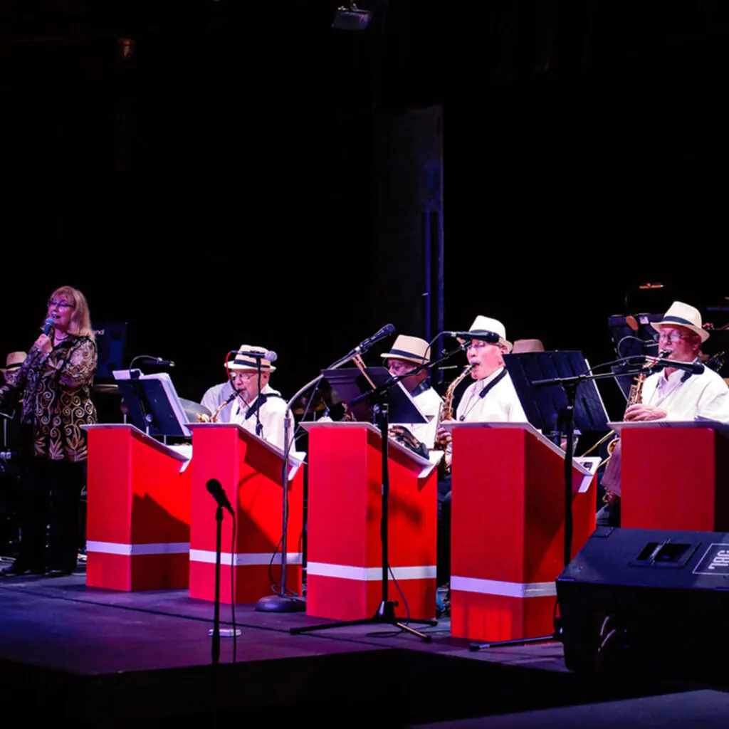 Musicians on stage with red music stands