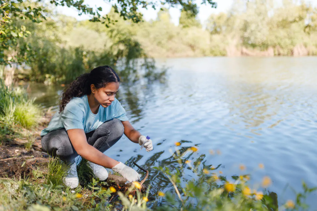 A woman collects a water sample from a lake for environmental conservation purposes