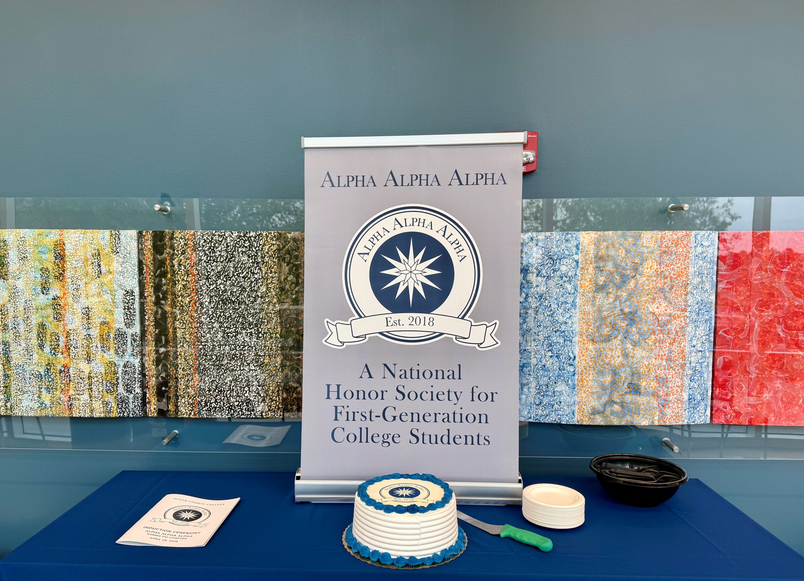 table with a banner for Tri-Alpha and a cake with the logo on it.