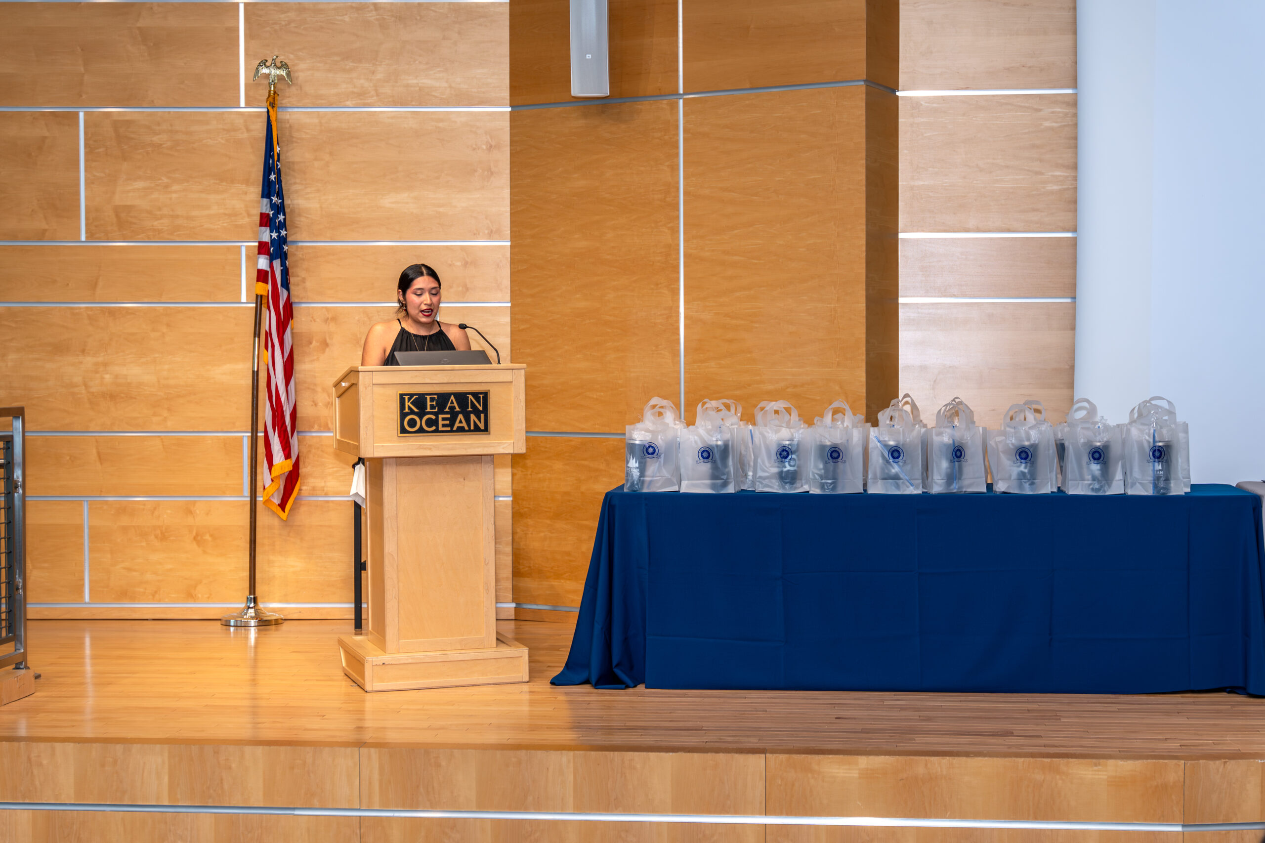 Female with black hair standing at a podium giving a speech.