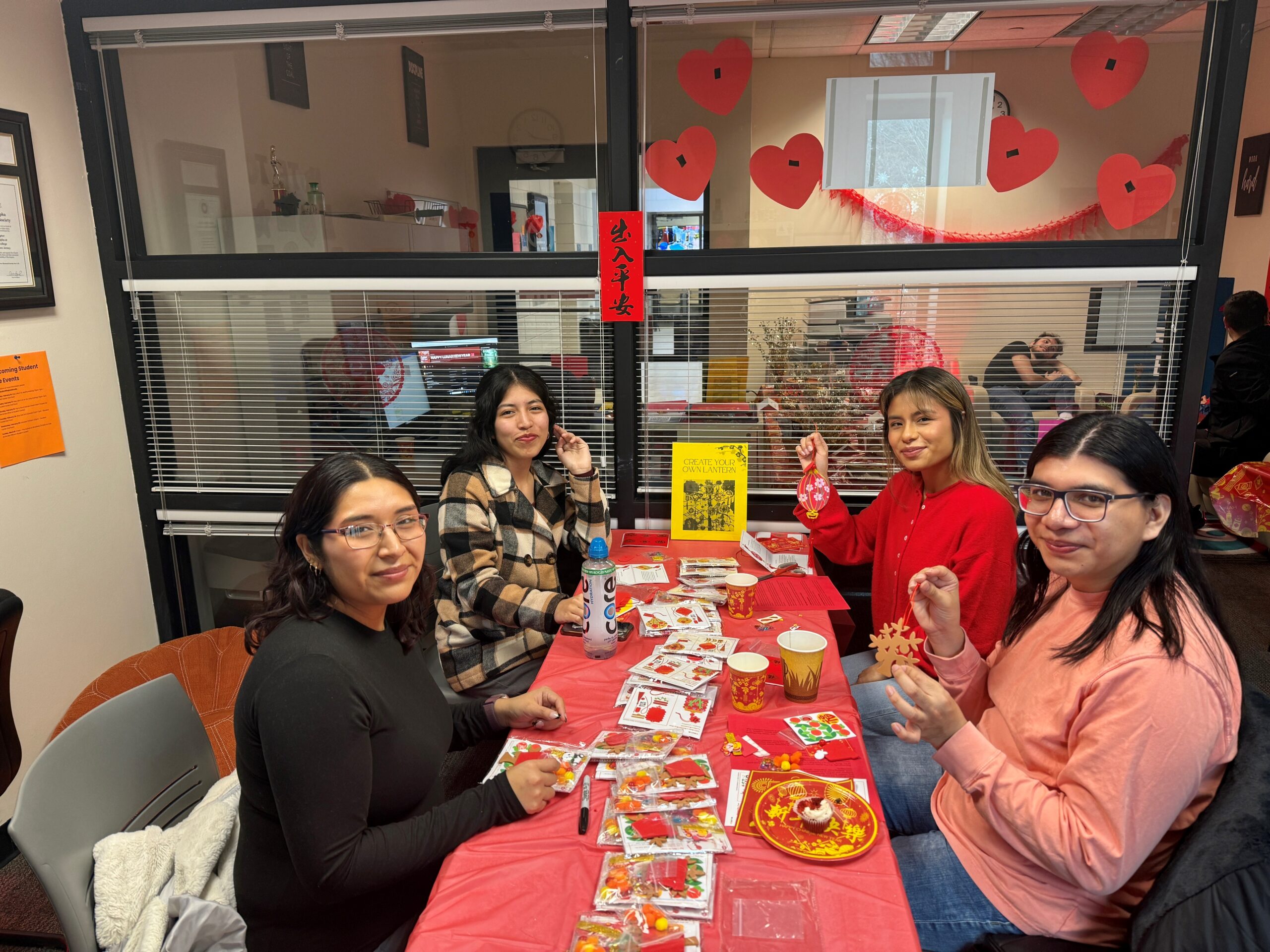 Four students sitting at a table working on lunar new year themed crafts.