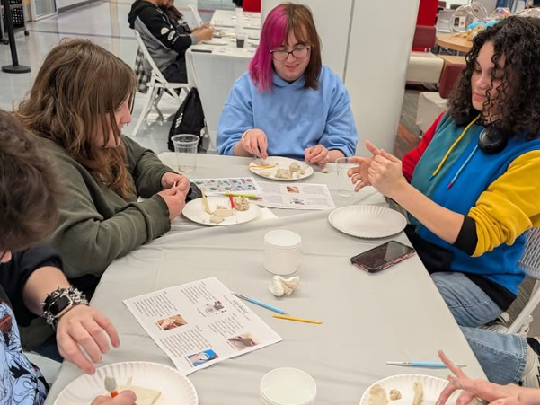 Group of people eating snacks at a table during a workshop, with papers and cups on the table.