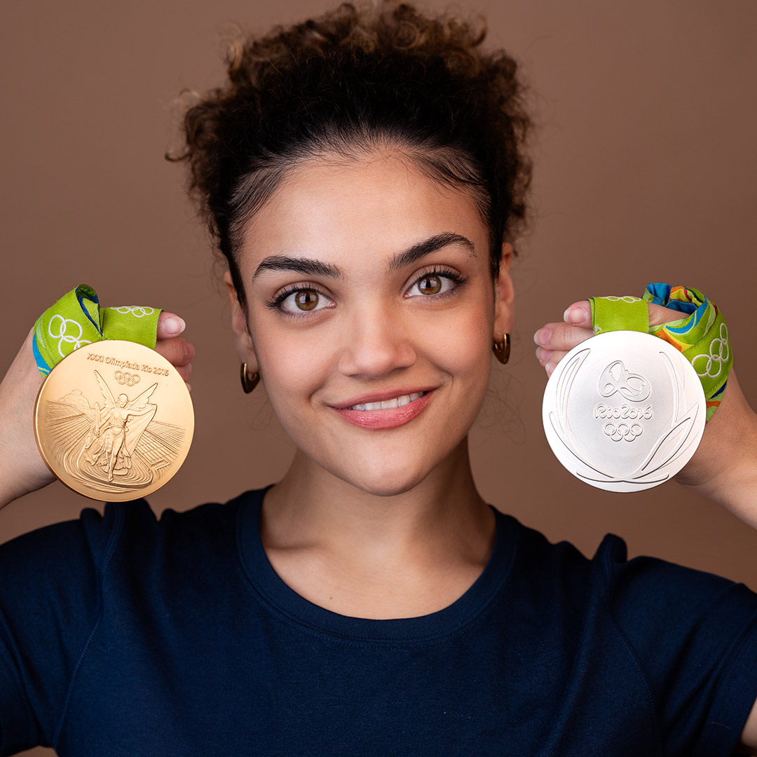 A person holding a gold and a silver Olympic medal.